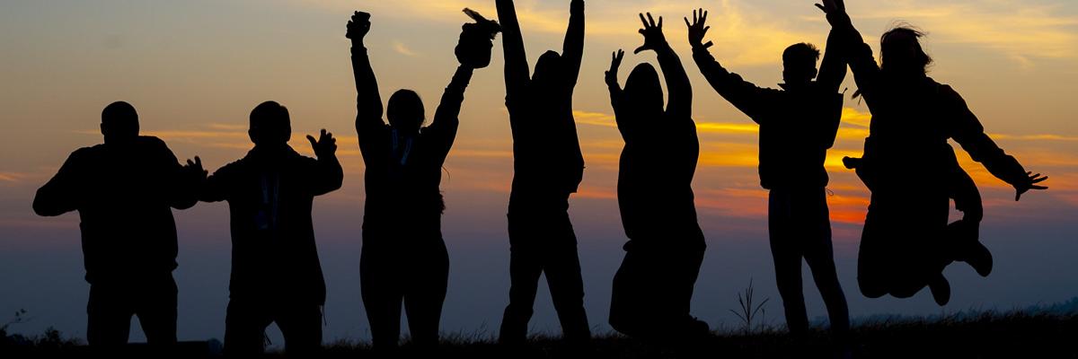 Leaping people in silhouette against sunset